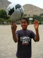 Ein junger Junge posiert mit einem Fußball in einem Outdoor-Sportbereich.