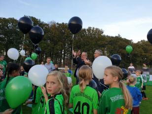 Eine Gruppe von Kindern und Jugendlichen bei einem sportlichen Event im Freien, umgeben von vielen Ballons.