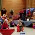 Viele spielende Kinder und Erwachsene in einer großen Turnhalle mit Spielgeräten und Matten.