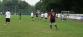 Mehrere Fußballspieler spielen auf einem großen grünen Rasenfeld.