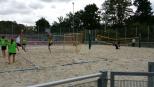 Ein Volleyballspiel auf einem Sandplatz mit mehreren Spielern und Netzen.