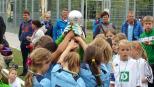 Eine große Gruppe junger Menschen in blau-weißer Sportkleidung posiert gemeinsam im Freien vor einem Sportzaun.