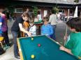 Eine Gruppe von Jungen spielt draußen an einem Pooltisch.