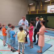Eine Gruppe von Familien und Kindern befindet sich in einer großen Sporthalle mit Basketballkörben.