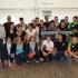 Eine große Gruppe von Kindern und Jugendlichen in Sportkleidung posiert für ein Gruppenfoto in einer Sporthalle.