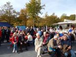 Eine Gruppe von Menschen versammelt sich bei einem Outdoor-Event inmitten von Bäumen.
