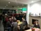 Innenansicht eines belebten Restaurants oder Geschäfts mit vielen Kunden und einem Kaminbereich.