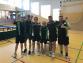 Eine Gruppe junger Männer in Sportkleidung steht in einer Sporthalle.