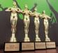 Fünf goldfarbene Trophäen, die sportliche Auszeichnungen darstellen, stehen nebeneinander, darunter sind Plaketten mit Jahresangaben angebracht.