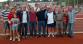 Eine große Gruppe von Menschen, die freudig auf einem Sportplatz für ein Gruppenfoto posieren.