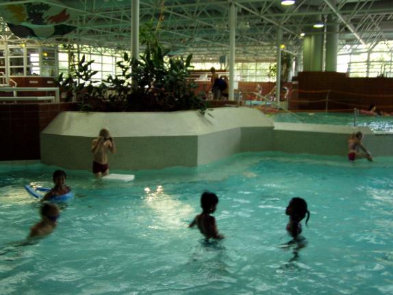 Mehrere Personen schwimmen in einem großen, überdachten Innenpool.