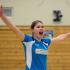 Eine junge Sportlerin, die in einer Sporthalle mit weit ausgestreckten Armen in Aktion festgehalten wird.