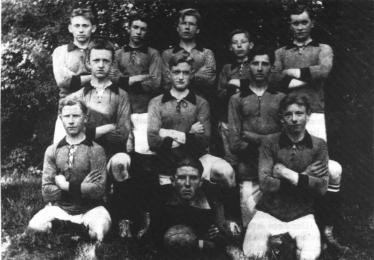 Schwarzweißfoto einer Gruppe von jungen Männern, die wie ein Sportteam posieren.