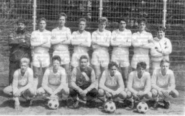 Historisches Gruppenfoto eines Fußballteams in alter Sportkleidung vor einem Netz.