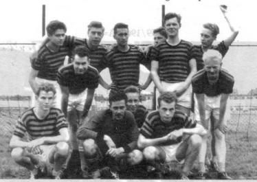 Eine große Gruppe von Männern, wahrscheinlich ein Sportteam, posiert in mehreren Reihen für ein Schwarz-Weiß-Foto im Freien.