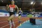 Drei männliche Athleten absolvieren einen Sprintlauf auf einer Indoor-Bahn.