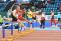 Mehrere männliche Athleten rennen während eines Sprintwettkampfs auf einer Tartanbahn in einer Sportarena.