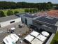 Ein großer, moderner Gebäudekomplex mit Solaranlagen, umgeben von verschiedenen Sportplätzen und Wäldern.